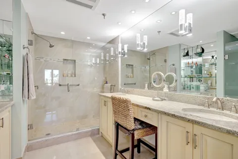a bathroom with a granite countertop shower a sink and mirror