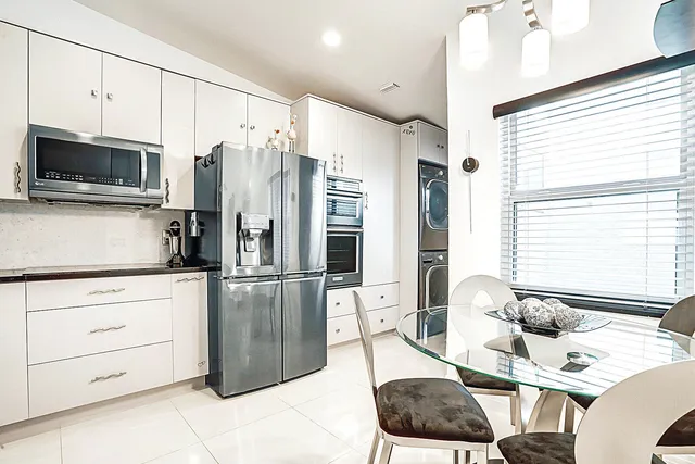 a kitchen with stainless steel appliances kitchen island granite countertop a refrigerator a stove top oven a sink and a dining table with wooden floor