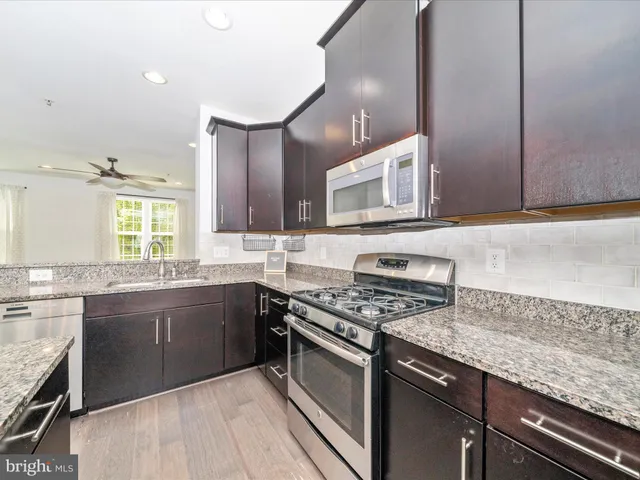a kitchen with stainless steel appliances granite countertop a stove top oven a sink dishwasher and cabinets with wooden floor