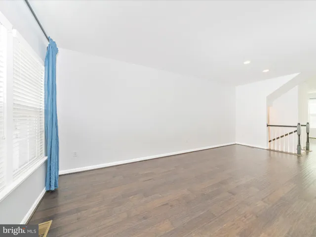 a large white kitchen with stainless steel appliances kitchen island a large counter top a stove and a wooden floor