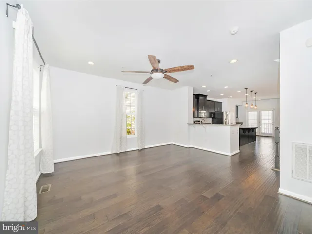 a kitchen with stainless steel appliances granite countertop a sink a center island a refrigerator wooden floor and a window