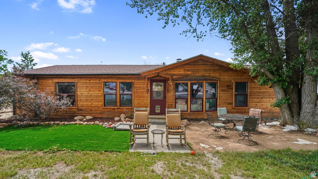 490 South Main Street Kamas, UT 84036 - Photo 1 of 25 Wood-sided residence featuring a covered front entry with a red door, multiple windows, and a brown shingle roof