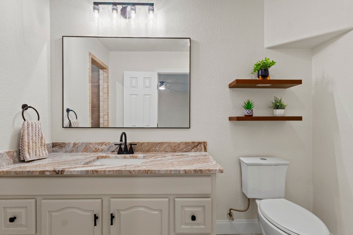 135 James Street Bridge City, TX 77611 - Photo 6 of 12 a bathroom with a granite countertop toilet sink and mirror