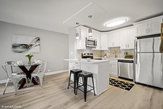 a kitchen with a refrigerator a white cabinets and chairs