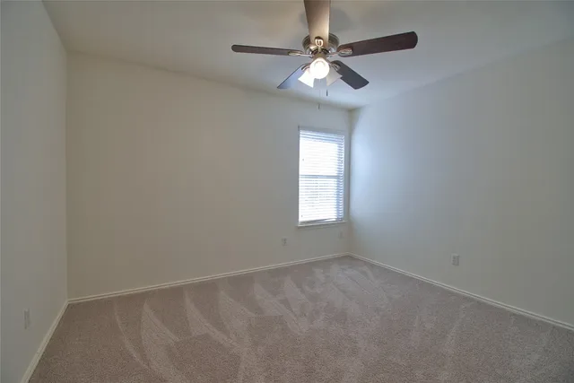 a view of an empty room and chandelier fan