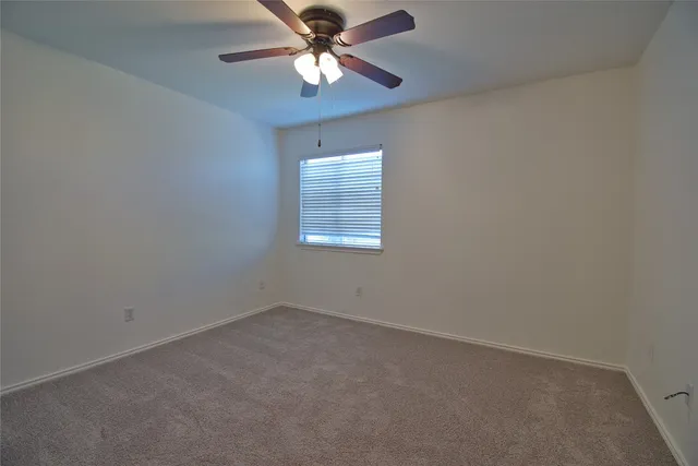 a view of an empty room and chandelier fan