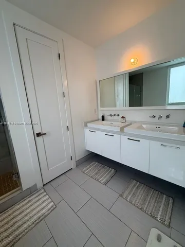 a bedroom with a bed and dresser with wooden floor