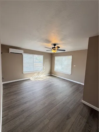 an empty room with wooden floor cabinet and windows