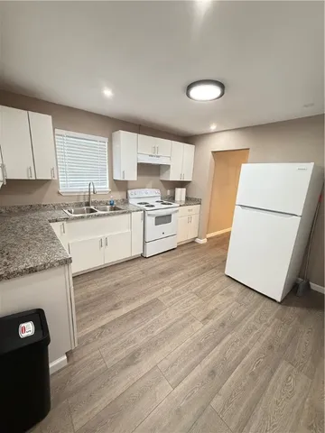 a kitchen with a sink a stove a refrigerator and white cabinets
