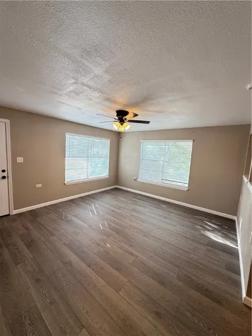 an empty room with wooden floor cabinet and windows