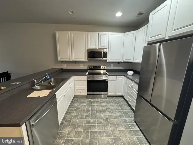 a kitchen with a sink a stove top oven and refrigerator