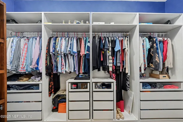 a view of walk in closet with clothes and shoes