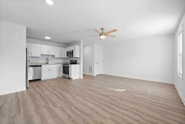 a view of an empty room with a window and wooden floor
