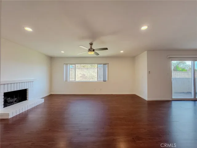 an empty room with wooden floor fireplace and windows