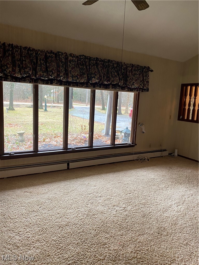 7316 Risden Road Vermilion, OH 44089 - Photo 8 of 22 Empty room with carpet, a baseboard heating unit, ceiling fan, and a healthy amount of sunlight