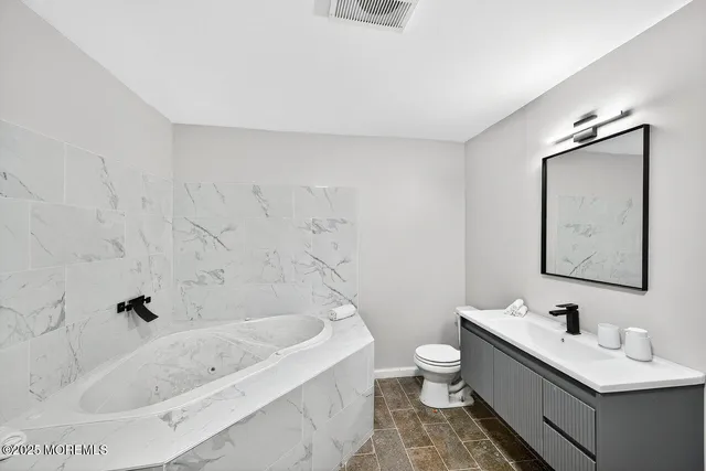 a bathroom with a tub sink toilet and mirror