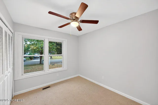 an empty room with ceiling fan and window