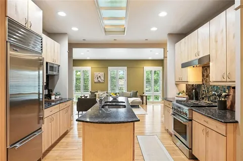 a kitchen with kitchen island granite countertop a sink a counter top space and living room view