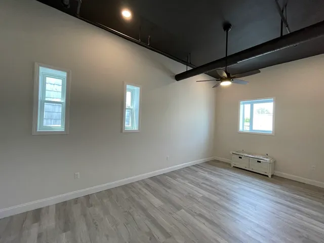 an empty room with wooden floor and windows