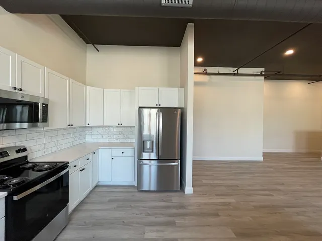 a kitchen with granite countertop a refrigerator and a stove top oven