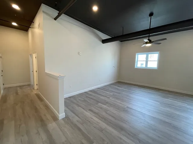 an empty room with wooden floor and windows