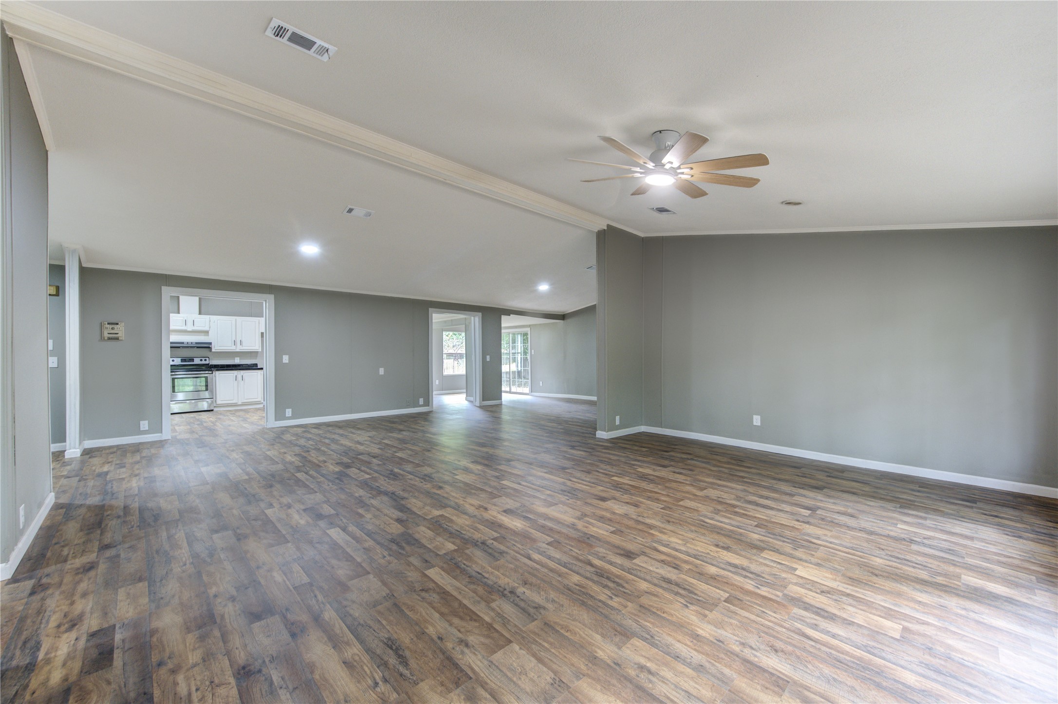 30226 Davis Street Magnolia, TX 77355 - Photo 9 of 50 This spacious, open-concept living area features modern wood flooring, neutral walls, and recessed lighting. It seamlessly connects to a kitchen with stainless steel appliances and offers ample natural light.