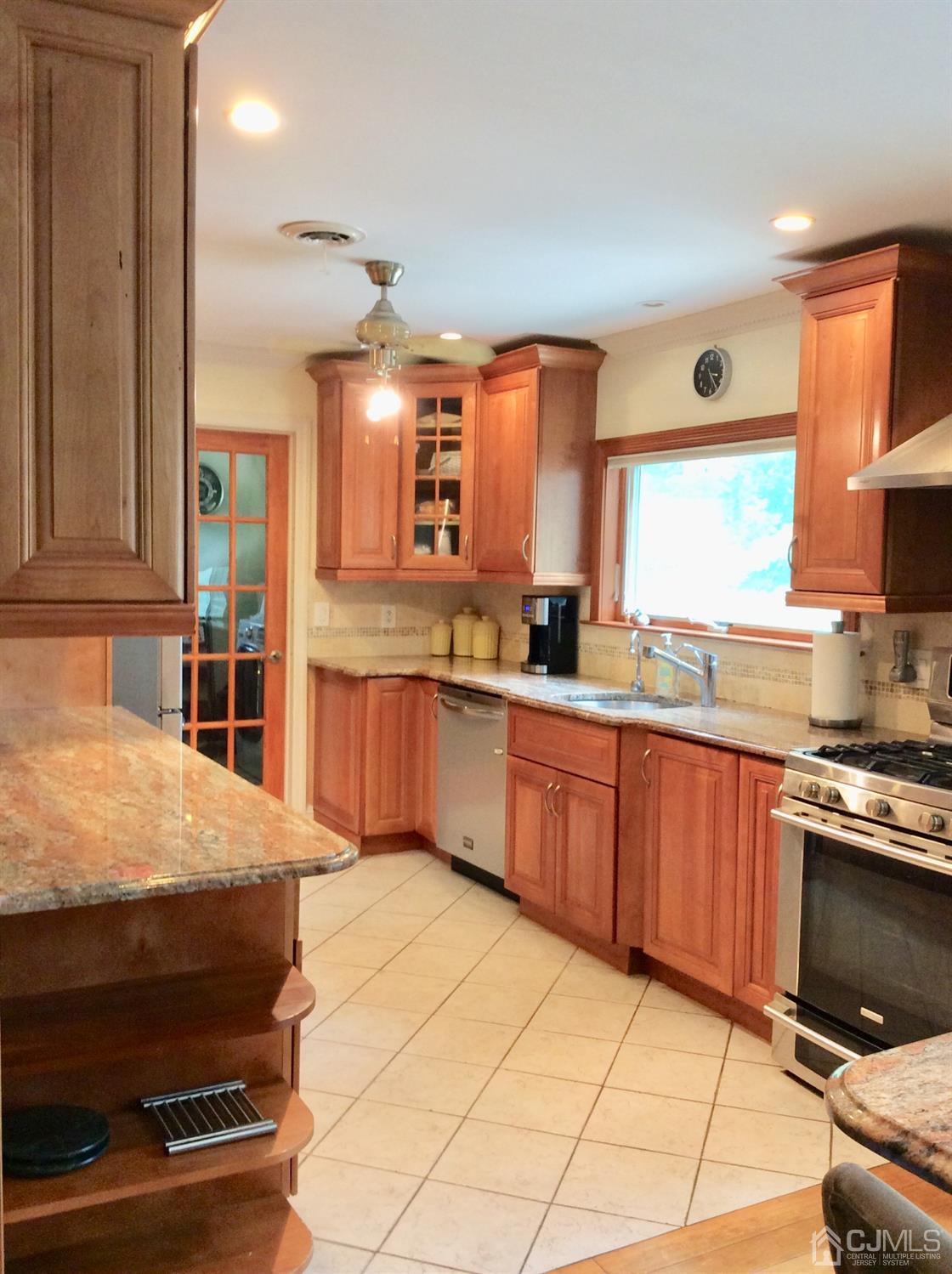 9 Devon Road Edison, NJ 08820 - Photo 46 of 58 a kitchen with stainless steel appliances kitchen island granite countertop a stove a sink and a microwave