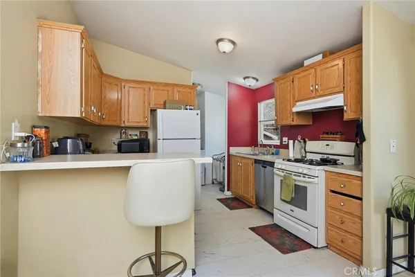 a kitchen with a refrigerator a stove a sink dishwasher and cabinets with wooden floor