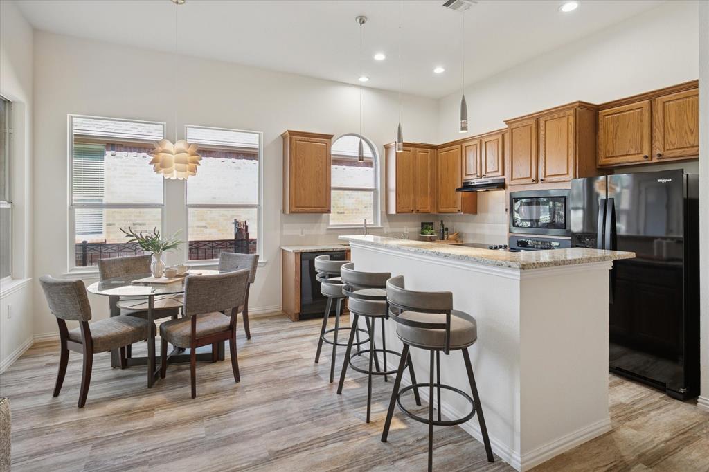 351 Rio Bravo Drive Fairview, TX 75069 - Photo 6 of 20 a kitchen with stainless steel appliances granite countertop a stove top oven a sink a dining table and chairs with wooden floor