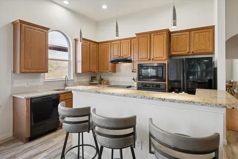 a kitchen with granite countertop a stove a sink and a refrigerator