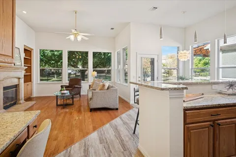 a view of a kitchen with kitchen island granite countertop a large window cabinets a sink and stainless steel appliances