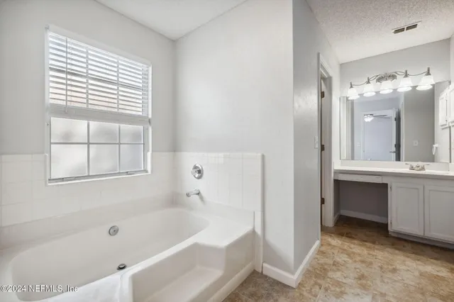 a bathroom with a tub sink and mirror