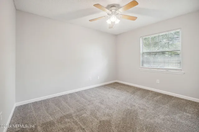 an empty room with a window and a fan