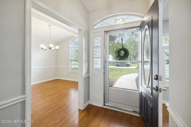 a view of a hallway with wooden floor and a dining room