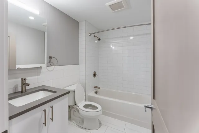 a bathroom with a granite countertop sink a toilet and shower