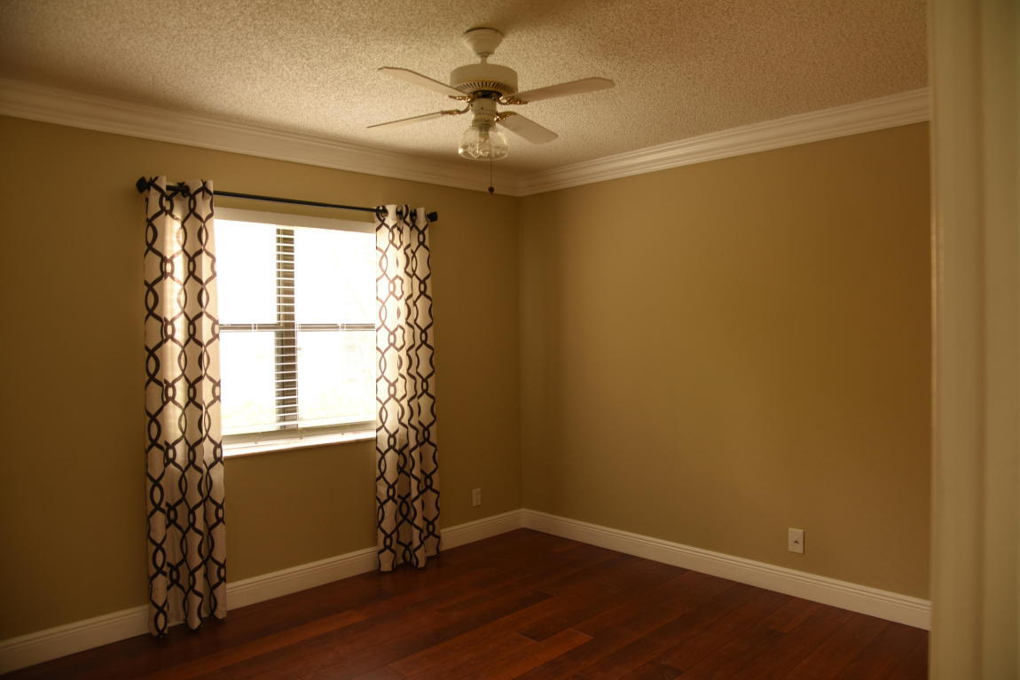 4465 Northwest 28th Way Boca Raton, FL 33434 - Photo 18 of 22 an empty room with wooden floor and windows with curtains
