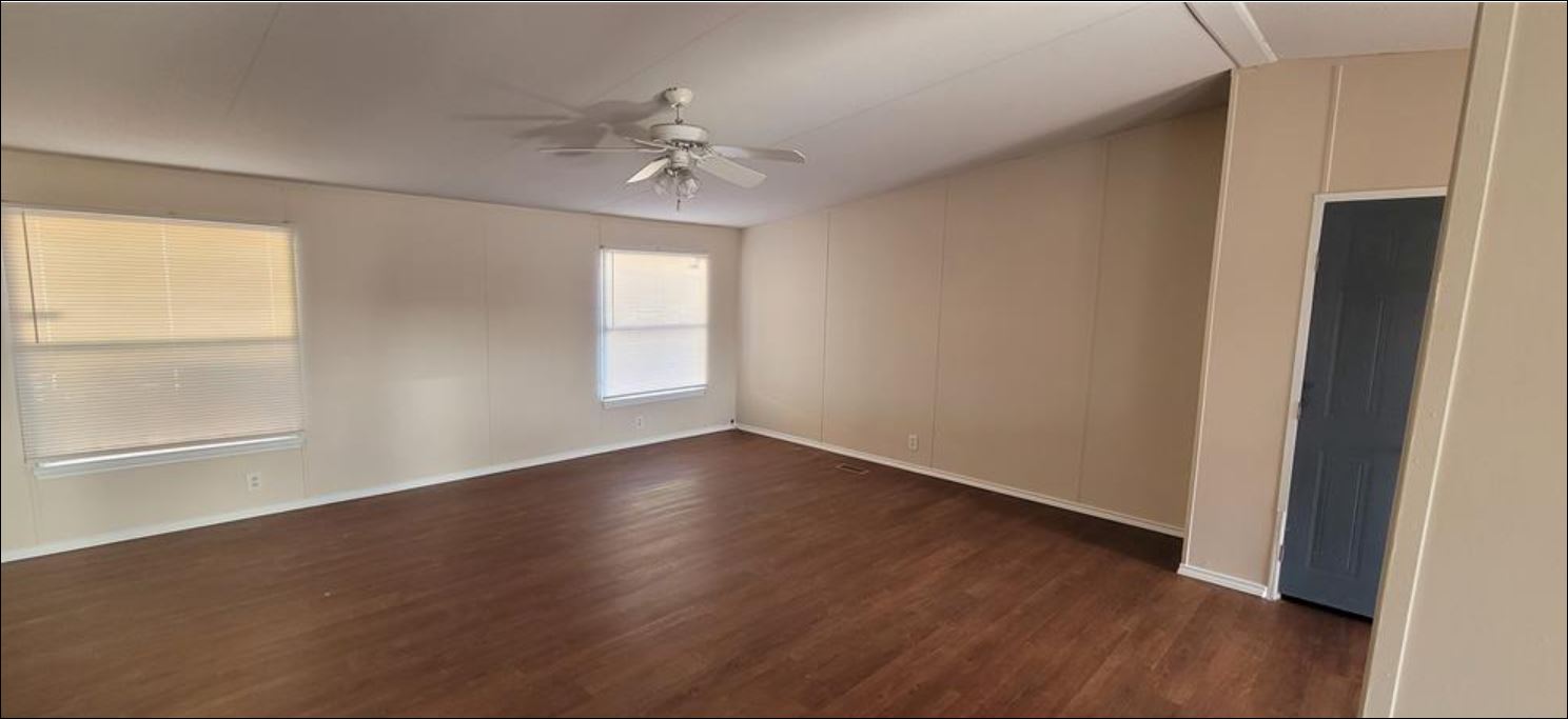 404 West Cleveland Street, Unit 1/2 Elgin, TX 78621 - Photo 18 of 23 Spare room featuring dark wood-type flooring, ceiling fan, and a decorative wall
