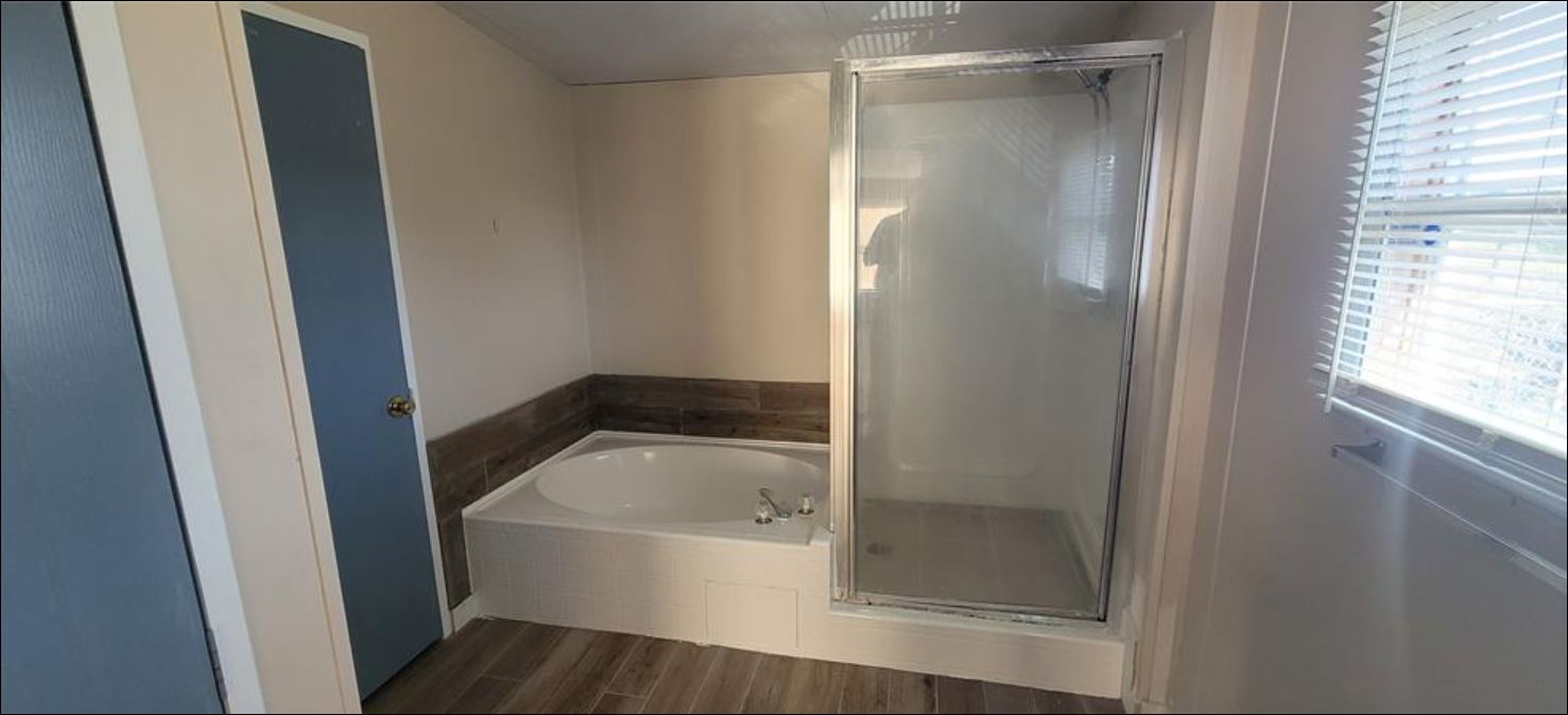 404 West Cleveland Street, Unit 1/2 Elgin, TX 78621 - Photo 22 of 23 Full bath with a shower stall, a garden tub, and wood finish floors