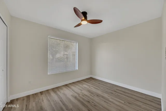 a view of empty room with wooden floor and fan