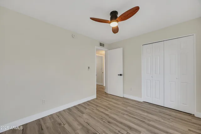 an empty room with wooden floor ceiling fan and window