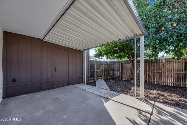a backyard of a house with lawn chairs and wooden fence