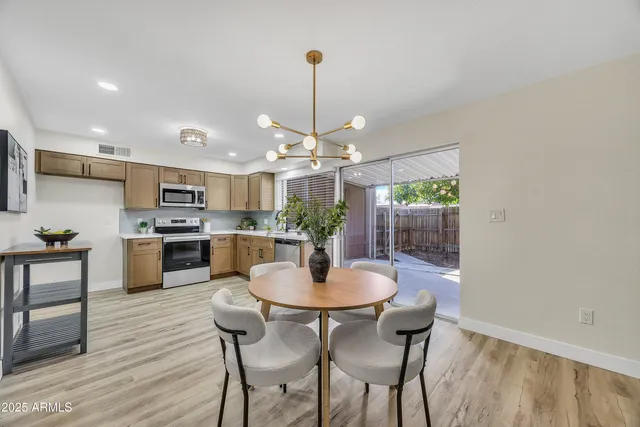 a kitchen with kitchen island a dining table chairs stainless steel appliances and cabinets