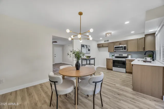 a kitchen with a dining table chairs stainless steel appliances and cabinets