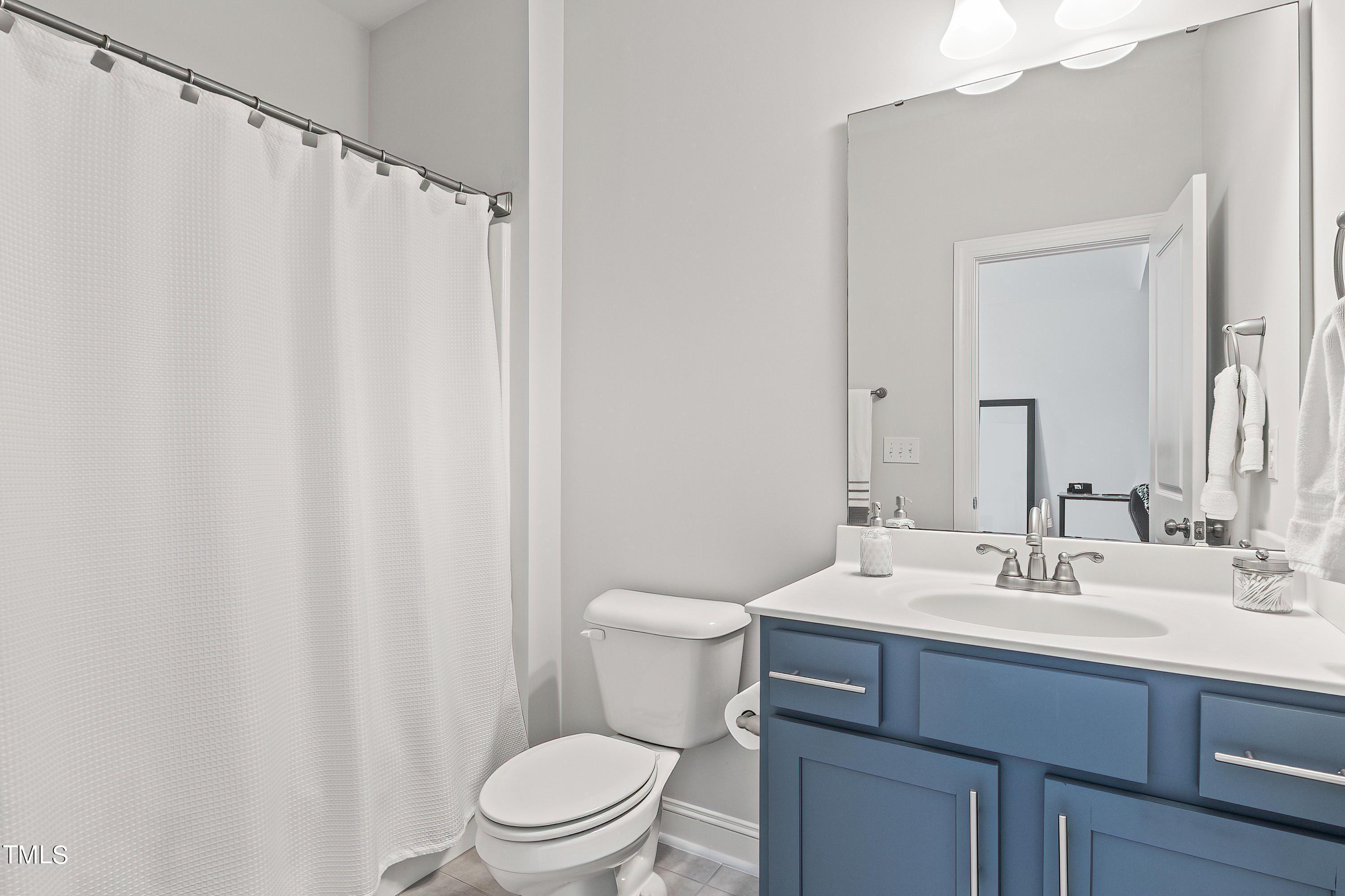 2025 Braeburn Drive Apex, NC 27539 - Photo 28 of 71 a bathroom with a sink a toilet and shower curtain