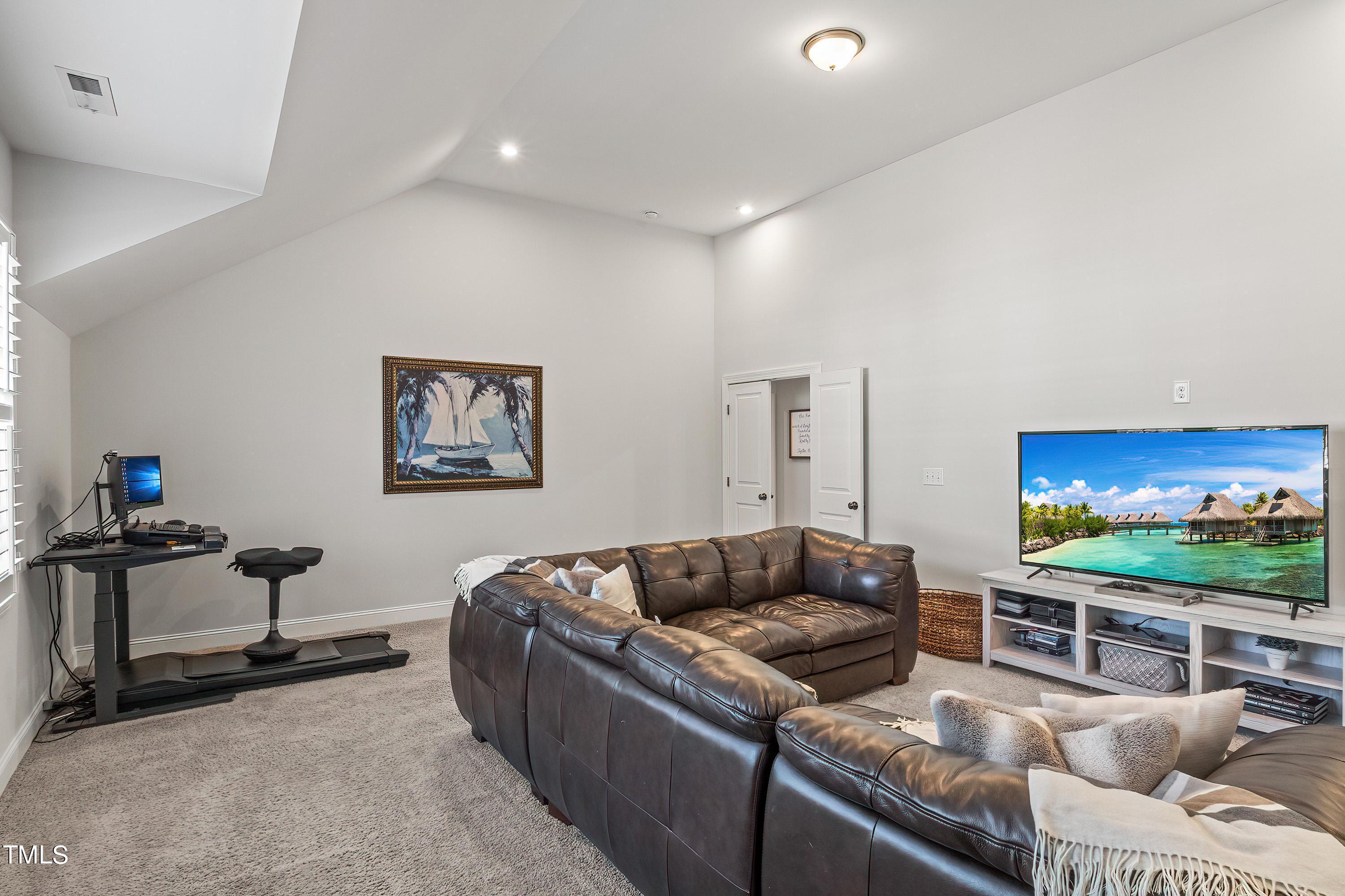 2025 Braeburn Drive Apex, NC 27539 - Photo 39 of 71 a living room with furniture and a flat screen tv