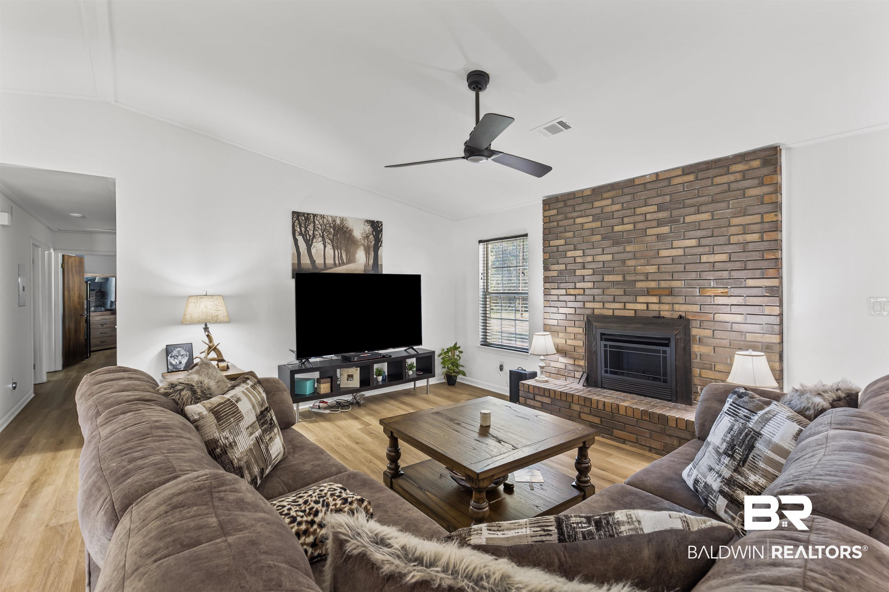 8911 Owassa Road Evergreen, AL 36401 - Photo 9 of 24 Living area featuring lofted ceiling, light wood-style floors, a brick fireplace, and ceiling fan