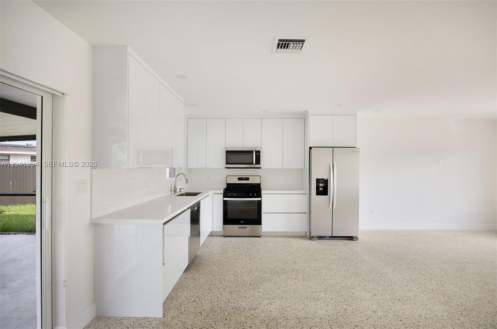 10340 Southwest 157th Street Miami, FL 33157 - Photo 5 of 24 Kitchen – Modern kitchen featuring sleek cabinetry, solid-surface countertops, and stainless steel appliances. Designed for both functionality and style, with ample workspace and storage.