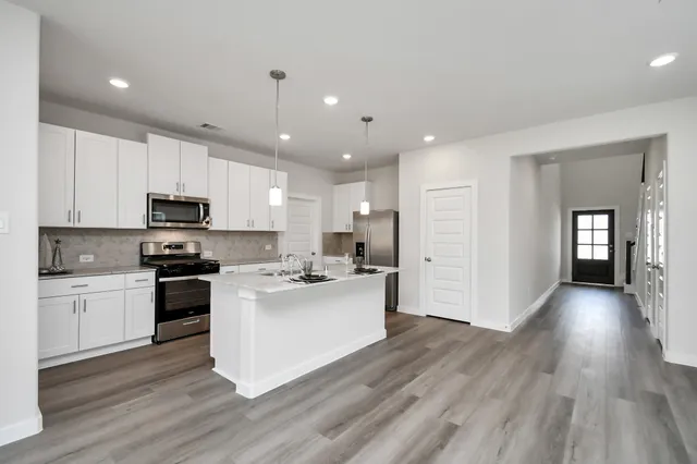 a kitchen with stainless steel appliances kitchen island a white cabinets and stove top oven