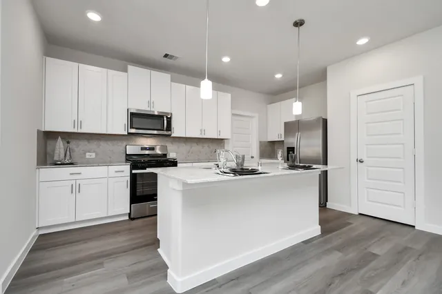 a kitchen with stainless steel appliances granite countertop a sink a stove a refrigerator and cabinets