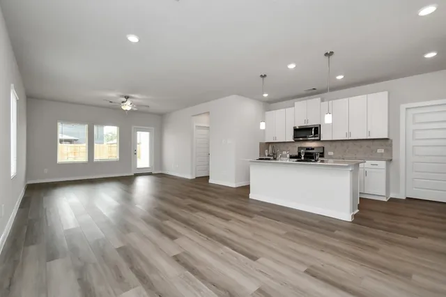 a view of an empty room with wooden floor and window